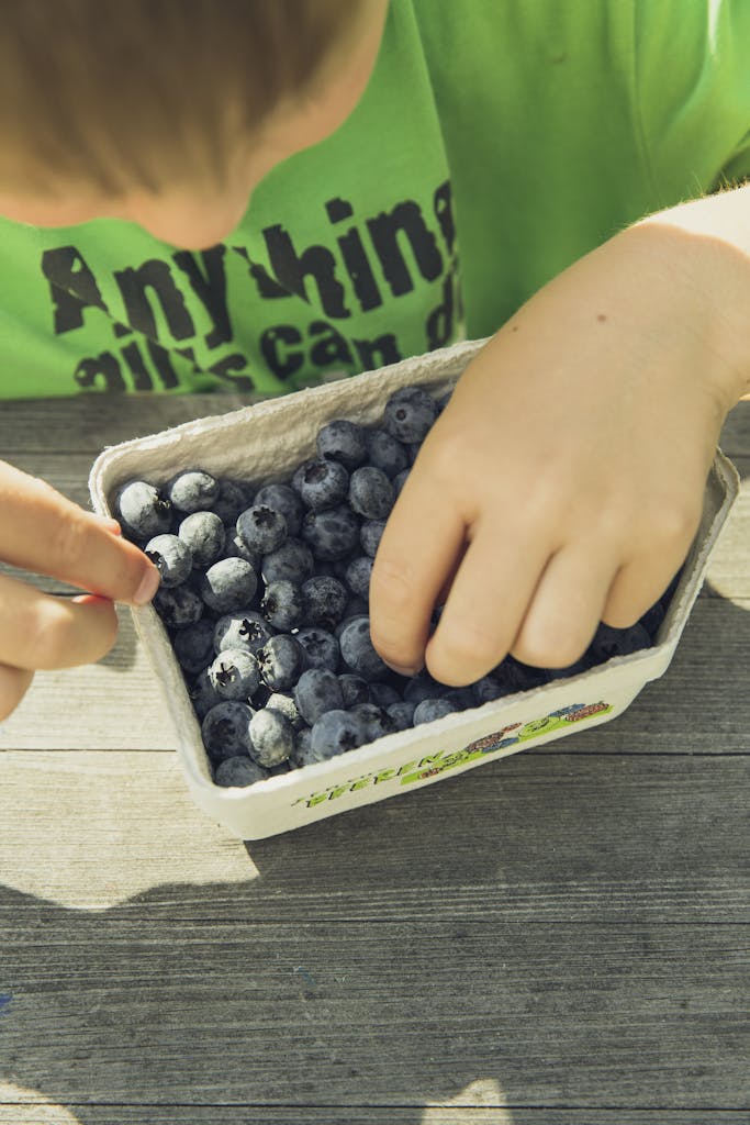 Person Holding Gray and Green Plastic Container With Black Beans